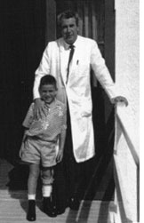 Bill Bell in his physiotherapy coat with a young boy, 1950s